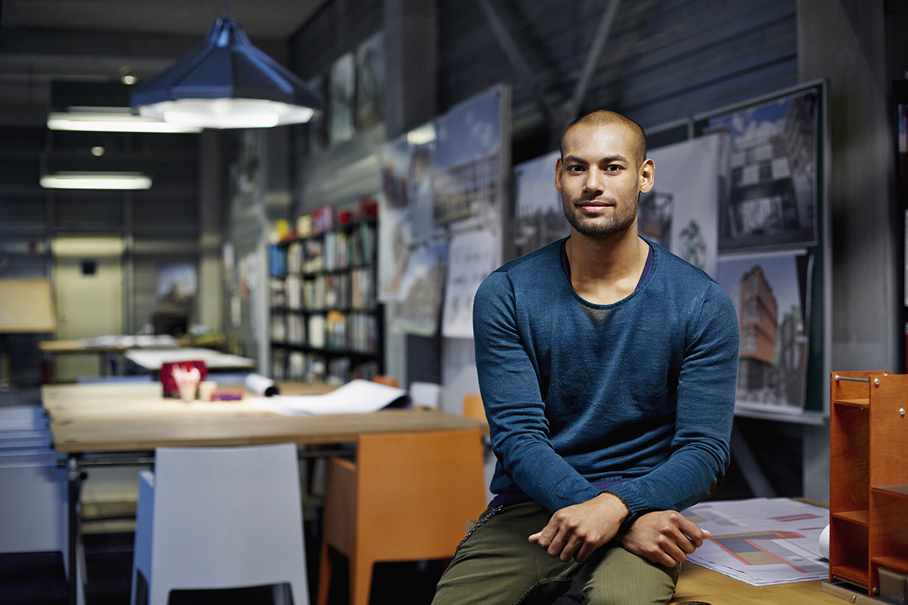 Man sat in flexible workspace in London with tables, chairs and a workspace behind him