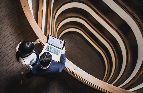 An image of people standing on a spiral staircase whilst looking at a computer