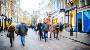 Busy shopping street with colourful storefronts and pedestrians, London, UK