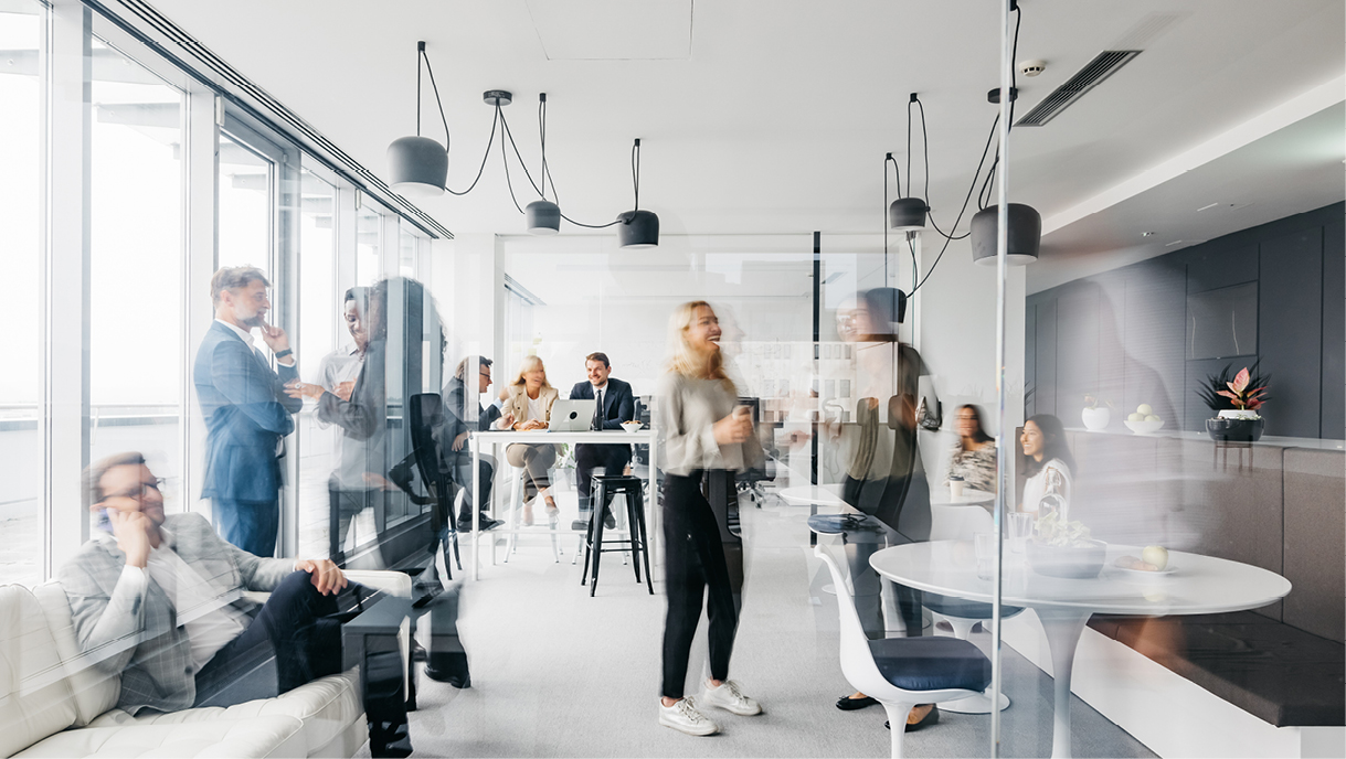 Busy modern office with employees working and interacting in a bright open-plan space