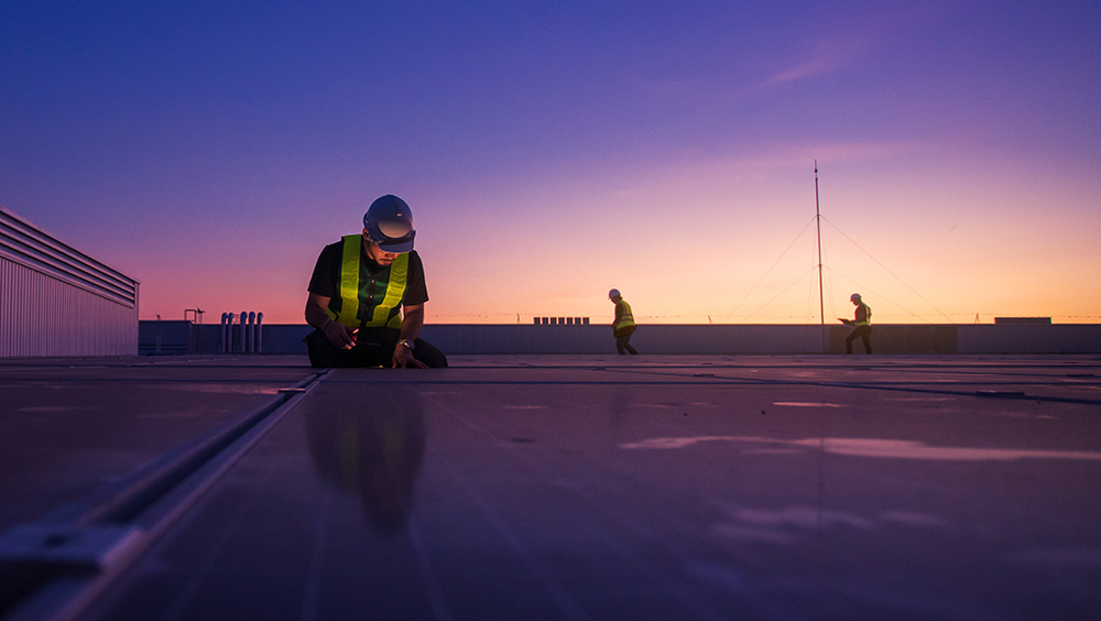 Engineers on roof looking at solar panels for decarbonisation of a building