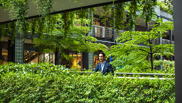 Green building in city centre of London with professional male walking through courtyard