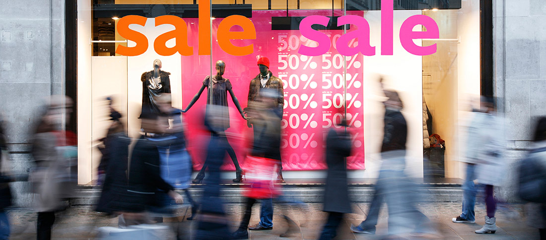 Sale signs in shop window at London's shopping street, motion blurred people present