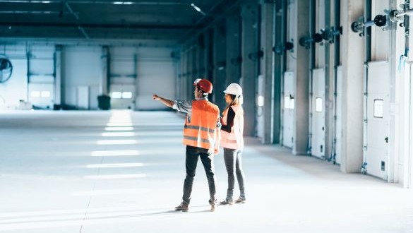 templafy-two-construction-workers-discussing-plans-in-a-large-empty-warehouse-1